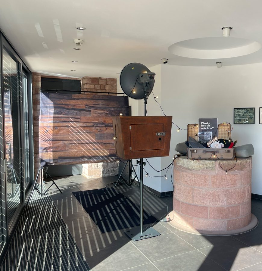 Mobile Fotobox im Holzgehäuse mit Studioblitz, Lichterkette und Holz-Fotohintergrund