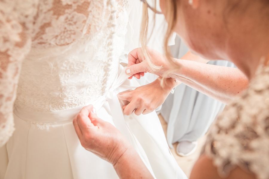 Das Brautkleid wird beim Getting Ready geschlossen – Detail