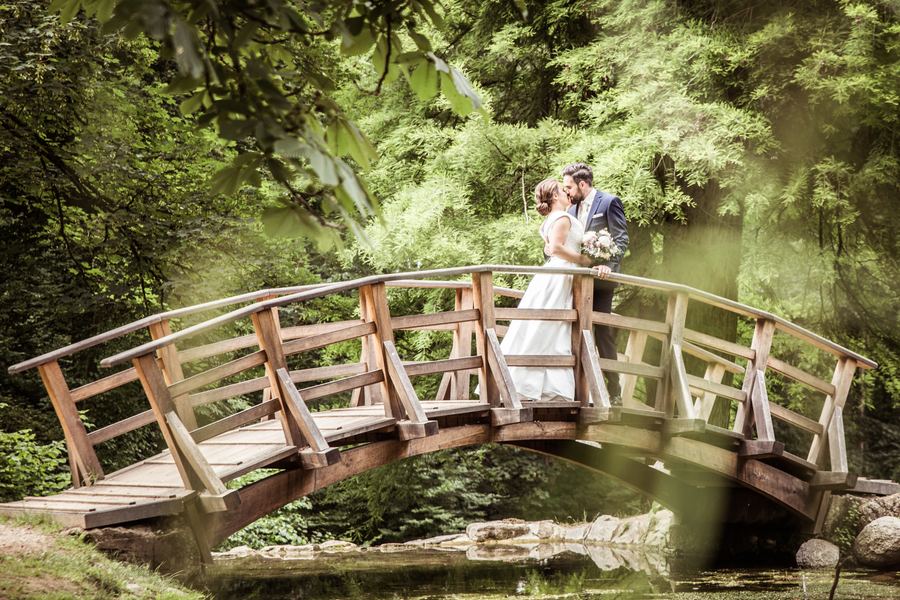 Brautpaar auf einer Holzbrücke im grünen Wald